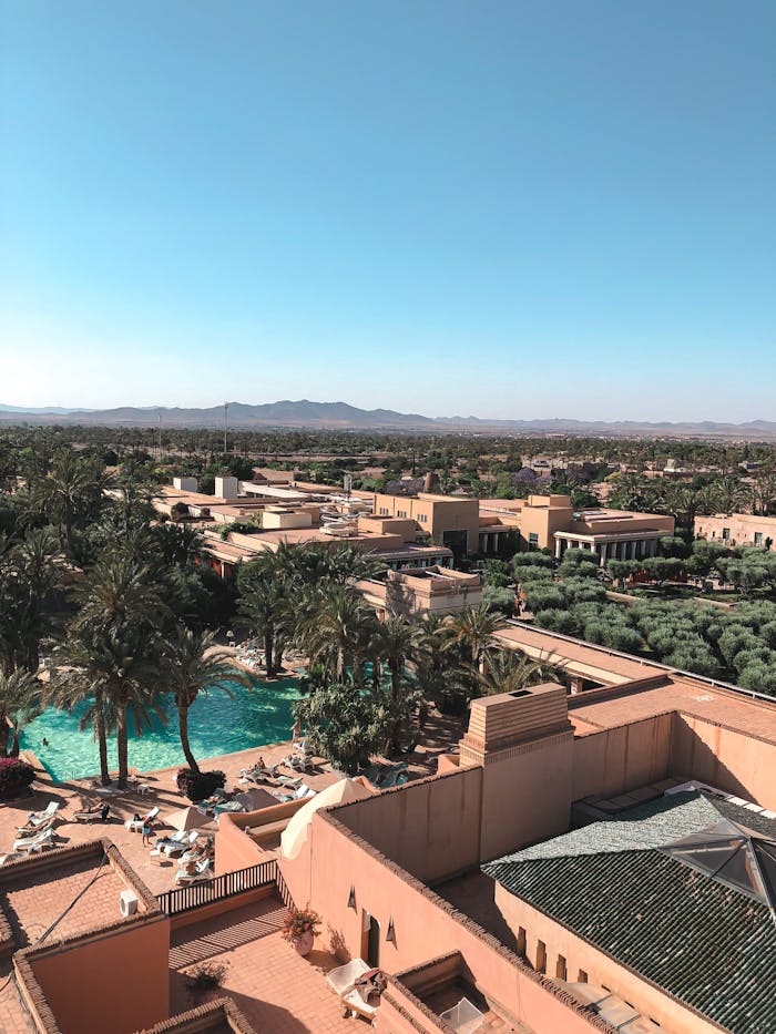 Aerial view of a luxurious tropical resort with palm trees and swimming pool under a clear blue sky.